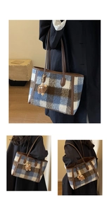 Detail view of a large plaid wool tote bag with brown leather straps and a fuzzy charm