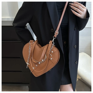 Brown heart-shaped crossbody bag with silver chains and rivets on a minimalist model