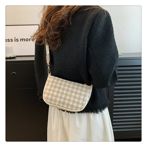 Chic beige houndstooth crossbody bag worn by a model in a minimalist interior setting
