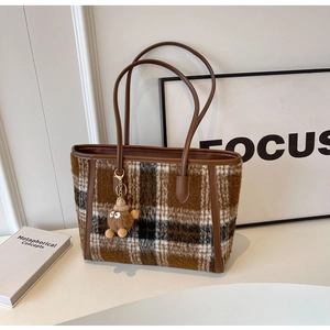 Detail view of retro plaid wool tote bag with leather straps and cute plush pendant