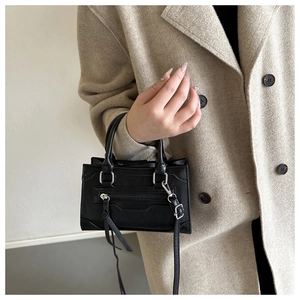 Detail of a black leather crossbody bag with silver hardware and tassel accents