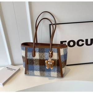Close-up of blue and brown checkered wool tote bag with a cute bear charm detail