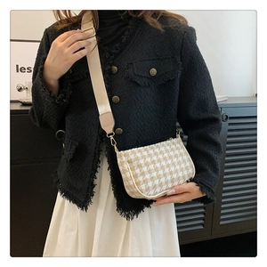 Classic houndstooth crossbody bag with wide shoulder strap worn by a model in modern interior