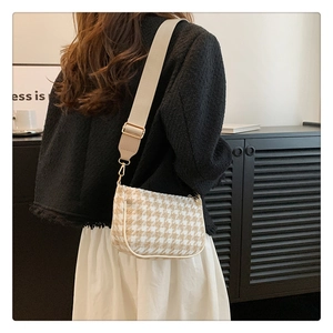 Detail of houndstooth crossbody bag showing khaki pattern texture and wide shoulder strap