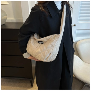Détail d'un sac bandoulière matelassé crème avec étiquette mode en tissu doux