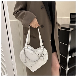 Close-up of heart-shaped crossbody bag with silver chains and cross charms