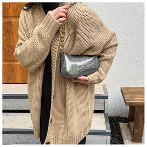 Borsa baguette laser argento con catena dorata abbinata a un cardigan in maglia
