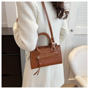 Detailed side view of a brown faux leather motorcycle crossbody bag with tassel zippers