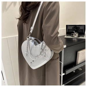 Close-up of heart-shaped silver shoulder bag with metal chain and cross pendant detail