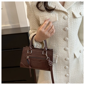 Close-up of a vintage brown crossbody bag featuring a classic smile structure design