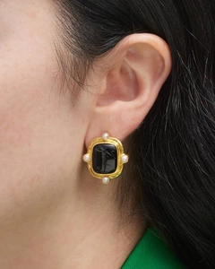 Vue rapprochée d'une boucle d'oreille baroque avec relief noir et perles blanches