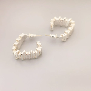 Modern C-shaped silver stud earrings featuring unique geometric textured surface