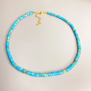 Détail de perles en pierre bleue texturée avec anneaux dorés et fermoir mousqueton