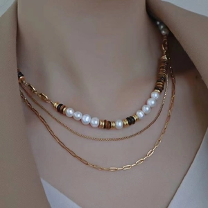 Three-layer gold necklace with pearls and paperclip chain worn on female neck