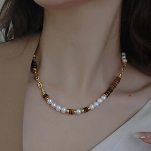 Elegant beaded necklace with white pearls, tiger eye stones, and gold coffee bean charm