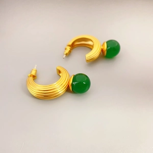 Vintage C-shaped gold-plated earrings with green chalcedony beads on grey background