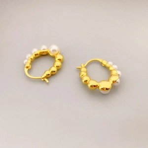 Elegant gold hoop earrings with irregular textured surface and white pearl accents