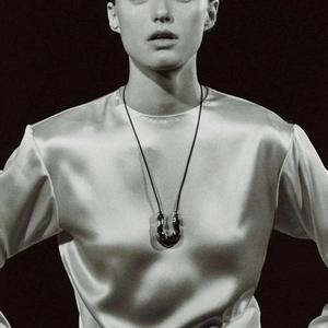 Polished liquid metal style U-shaped pendant on a simple black cord worn by a model