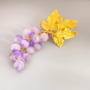 Close-up of vintage purple grape earrings featuring golden leaves and bead clusters