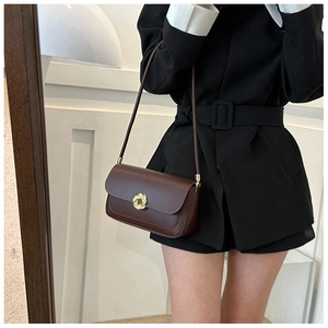 Detail of a vintage brown leather shoulder bag with a unique gold twist lock closure