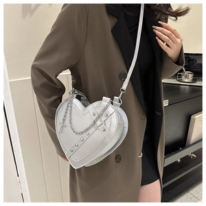 Detail of silver heart-shaped crossbody bag with rivets and cross chain accessory