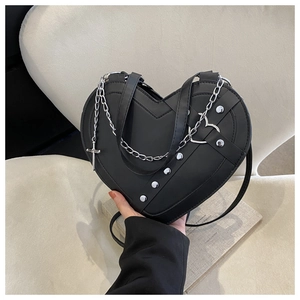 Detail view of heart-shaped black crossbody bag with silver studs and chain strap