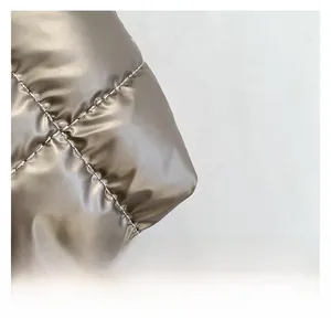 Macro detail of champagne gold quilted fabric with metallic satin finish and neat stitching