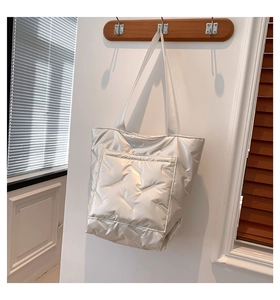 Detail of silver quilted tote bag with front pocket and glossy nylon texture
