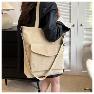 Detail of beige corduroy tote bag showing ribbed texture and adjustable strap