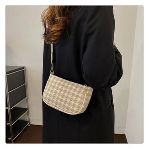 Close-up of houndstooth shoulder bag featuring elegant beige weave and gold metal hooks