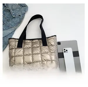 Quilted metallic gold tote bag showing capacity with a tablet and smartphone