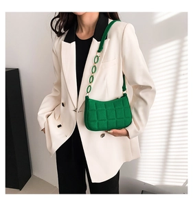 Detail der grünen gesteppten Hobo-Bag mit Kunststoffkette auf weißem Blazer