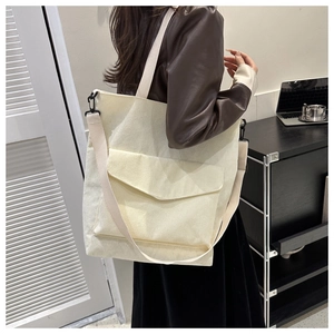 Detailed side view of large cream corduroy tote bag worn by model in a daily scene