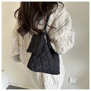 Détail du sac à bandoulière noir matelassé avec motif cœur et mini pochette zippée