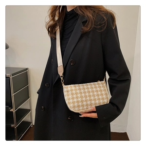 Detail of houndstooth crossbody bag showing woven texture and gold metal buckle