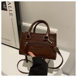 Detail of dark brown vintage luggage tote bag with metallic zipper and tassel