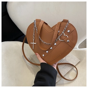 Detail of brown heart-shaped bag with silver chain, cross pendant and metal rivets