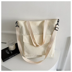 Close-up of beige corduroy tote bag showing textured fabric and black adjustable strap