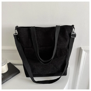 Close-up of black corduroy tote bag with adjustable shoulder strap and large front pocket