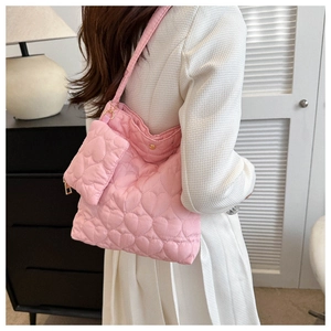 Détail du sac cabas matelassé rose avec breloque cœur assortie porté par un mannequin