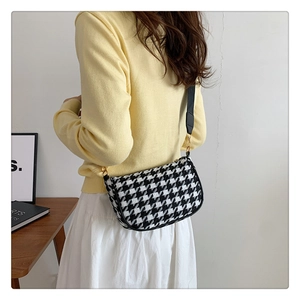 Detail of classic houndstooth saddle bag showing texture and black strap on model back