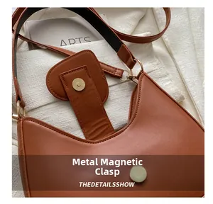 Dettaglio della chiusura magnetica in oro opaco sulla borsa a spalla in pelle color caramello