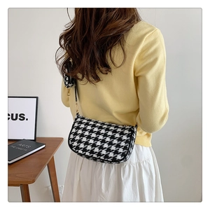 Detail of houndstooth shoulder bag with mini coin purse and gold hardware on a strap