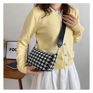 Detail of black and white houndstooth bag with wide canvas strap and gold hardware