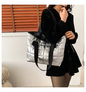 Detail of silver quilted tote bag with metallic finish and wide black shoulder straps