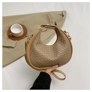 Detail of khaki woven crescent bag with adjustable strap and short handle on white