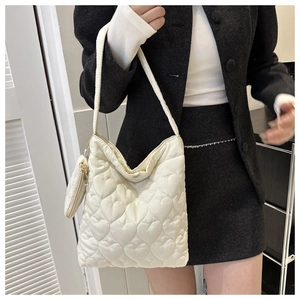 Détail de l'ensemble sac matelassé cœur blanc crème avec finitions dorées sur un mannequin