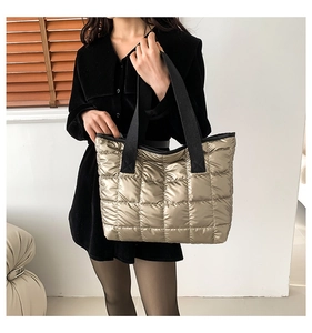 Quilted champagne gold tote bag with black strap shown on a model for casual style