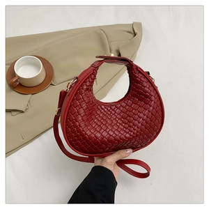 Detail shot of the woven texture and metal buckle on this dark red crescent hobo bag