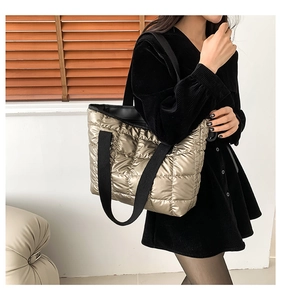Quilted champagne gold tote bag with black straps worn by model in a modern room setting